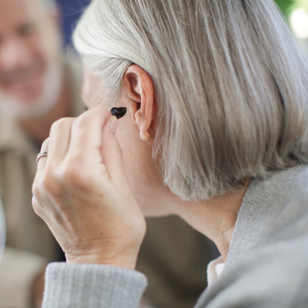 Woman-putting-CIC-in-ear Woman-putting-CIC-in-ear